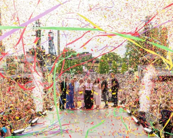 Tłum wiwatuje, a konfetti w żywych barwach, symbolizujące kolory Ostrawy, spada na scenę, gdzie stoi grupa ludzi.