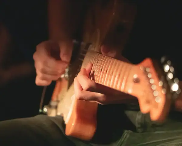 Ręce grające na gitarze elektrycznej, idealne do nauki jak nauczyć się grać na gitarze elektrycznej.
