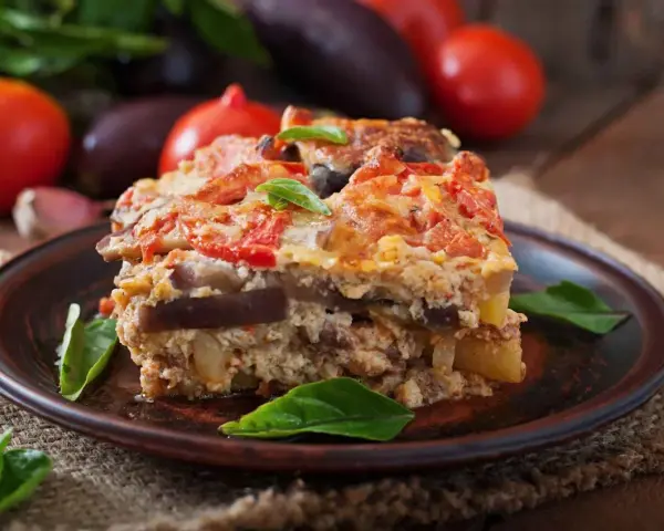 Un assaggio di cosa mangiare a Santorini: una saporita moussaka con melanzane, pomodori e formaggio, guarnita con basilico fresco.