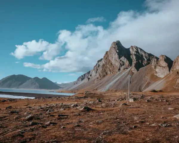 Surowe piękno Islandii. Góry, jezioro i sucha trawa. Nawet przy niskiej **temperatura Islandia** zachwyca.
