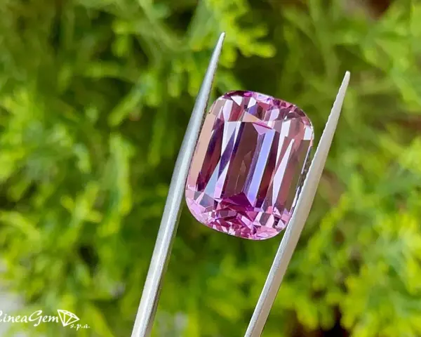 Una splendida kunzite rosa tenuta da una pinzetta, che ne esalta le proprietà e la brillantezza.