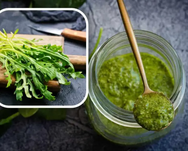 Un mazzetto di rucola fresca su un tagliere e un barattolo pieno di vibrante pesto di rucola, pronto per insaporire i tuoi piatti.