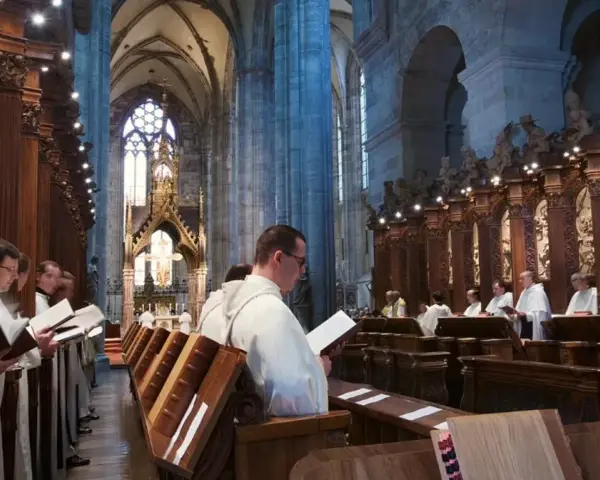 Men in white robes read from books in a grand cathedral, likely participating in matins, a morning prayer service.