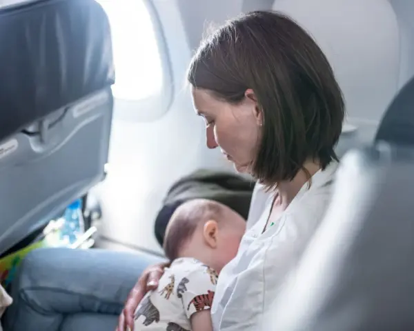 Mamma allatta il suo neonato di 6 mesi in aereo, un momento intimo durante il viaggio.