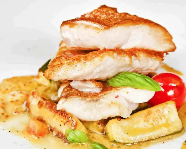 Piatto di pesce impanato e fritto, servito con verdure e salsa. Un'ottima scelta per il tuo menu di pesce.