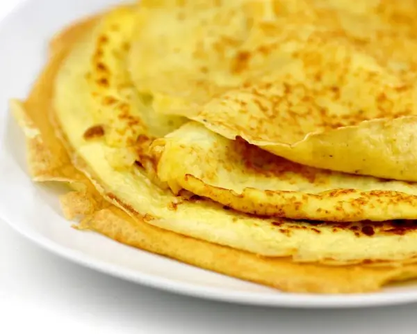 Ein Stapel goldbrauner Eierkuchen auf einem weißen Teller. Perfekt für ein schnelles und einfaches Eierkuchen Rezept.