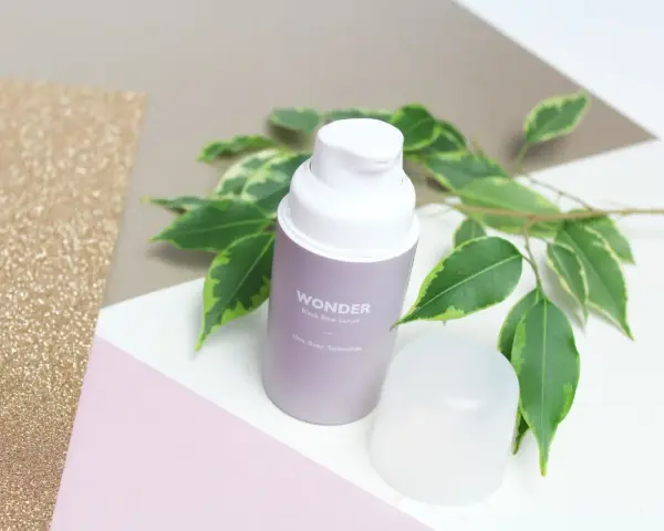 Wondeful! Serum z czarnego ryżu Haru Haru Wonder, otoczone zielonymi liśćmi, na tle błyszczącego złota i pastelowych kolorów.