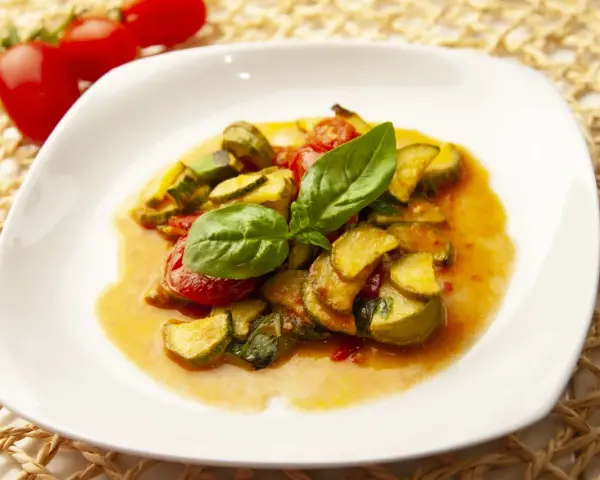 Zucchine in umido con pomodorini e basilico fresco, un piatto estivo profumato e saporito.
