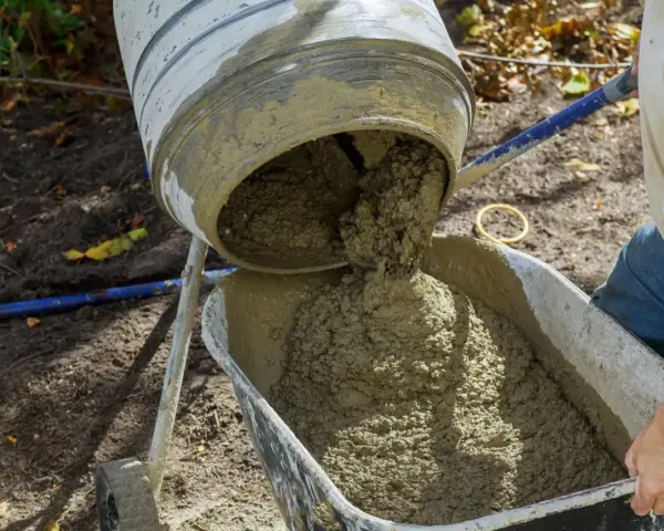 Betoniarka wylewa świeży beton do taczki. Oto jak zrobić beton w wiadrze, gdy potrzebujesz go do małych prac.