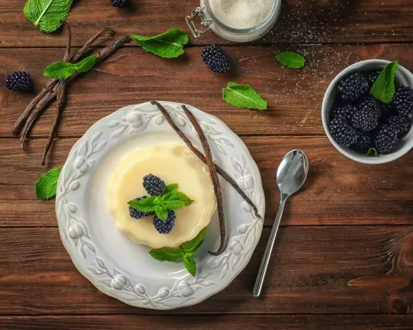 Budino fatto in casa alla vaniglia, guarnito con more fresche e menta. Ingredienti genuini per un dolce delizioso.