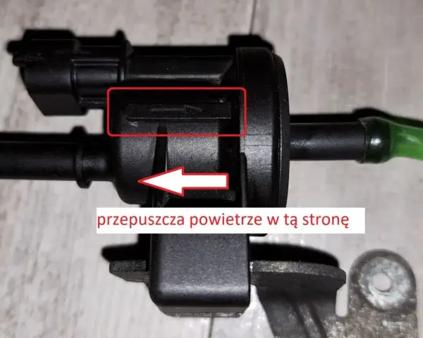 Zawór podciśnienia, potencjalna przyczyna błędu DTC P0170 w Volkswagen. Strzałka wskazuje kierunek przepływu powietrza.