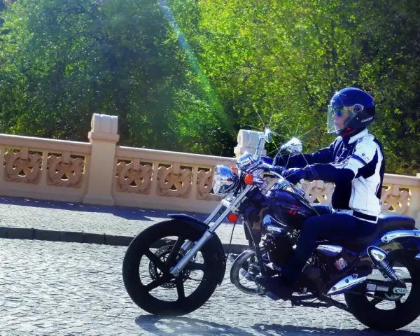 Motocyklista na Kymco Zing 125, zgrabnie pokonujący brukowaną ulicę. Dane techniczne tego modelu pozwalają na komfortową jazdę.