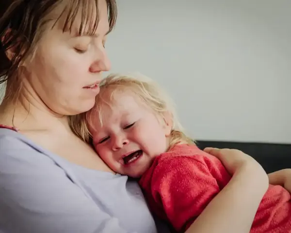 Mama tuli 2-latka, który płacze, przytula go mocno.