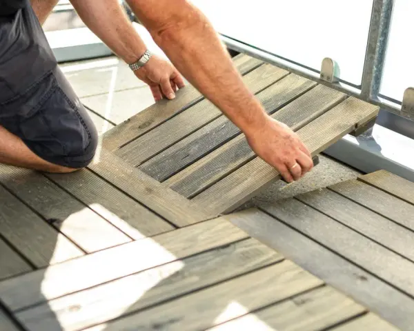 Mann legt Holzfliesen für den dachterrasse gestalten boden. Die Holzoptik passt gut zu modernen Außenbereichen.