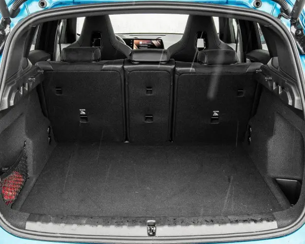 Otwarty bagażnik BMW X1, gotowy na podróż. Widoczne sportowe fotele i siatka z czerwoną gaśnicą.