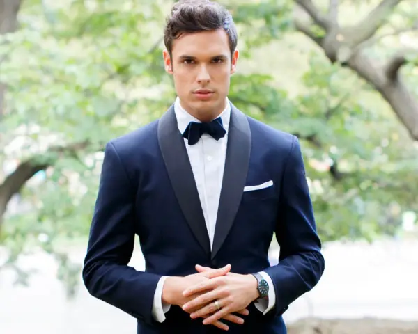 Uomo con smoking blu scuro, papillon e fazzoletto bianco. Il colore abito padre dello sposo è elegante e raffinato.
