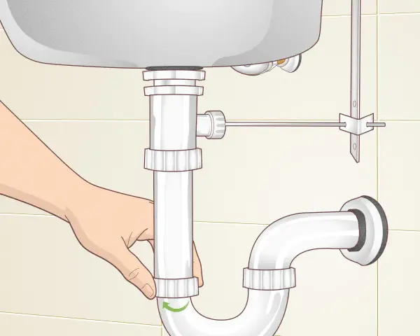 A hand loosens a pipe fitting under a sink, showing how to remove sink stopper.