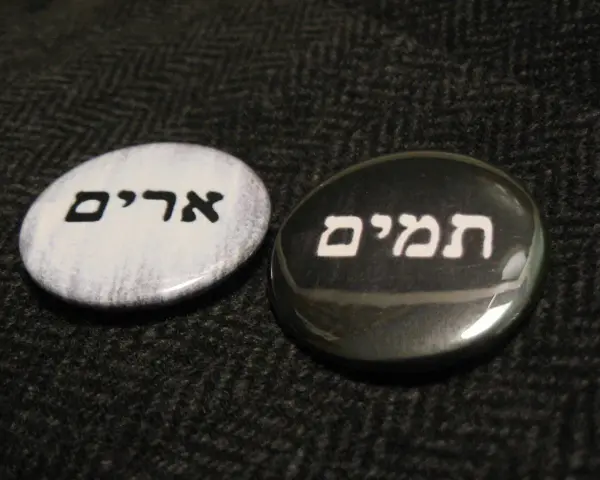 Two round pins with Hebrew text: "Urim" on a white background and "Thummim" on a black background.
