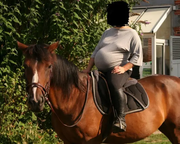 Une femme enceinte profite d'une balade à cheval, un moment de sérénité avant l'arrivée de bébé. L'équitation et grossesse, une combinaison harmonieuse.