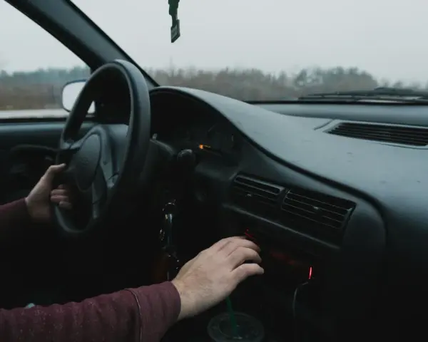 Dłoń kierowcy reguluje radio samochodowe.