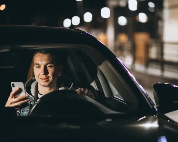 Mężczyzna w samochodzie Uber Black sprawdza telefon, planując trasę i licząc na dobre uber black zarobki.