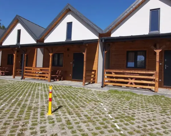 Drewniane domki na kempingu w Rewalu, z werandami i miejscami parkingowymi. Idealne na wakacje nad klifem.