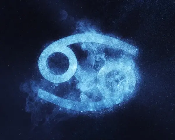 Błękitny symbol Raka, otoczony mgiełką i pyłem gwiezdnym, symbolizuje jego emocjonalne i opiekuńcze cechy charakteru.
