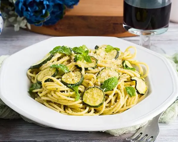 Un piatto di pasta e zucchine alla siciliana, guarnito con menta fresca e parmigiano.