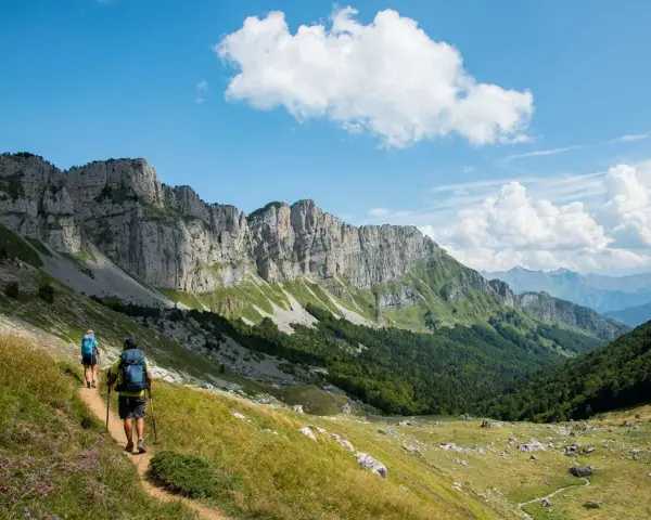 Deux randonneurs explorent un sentier escarpé au Pays Basque, sous un ciel bleu et des falaises imposantes.