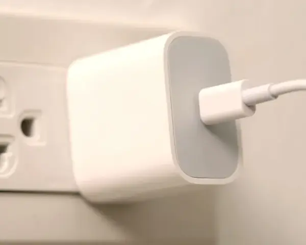 Biała ładowarka z kablem podłączona do gniazdka elektrycznego. Typ wtyczki EU.