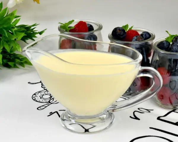 Krem custard i krem budyniowy w sosjerce, obok słoiczków z jagodami i malinami. Idealny deser na lato.