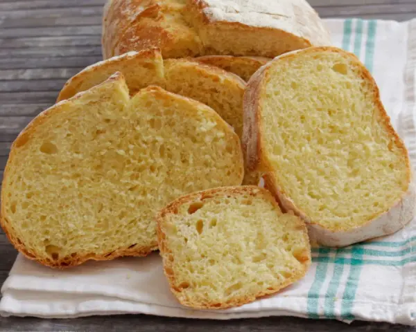 Fette di pane di semola dorato, con la crosta croccante e la mollica soffice, su un canovaccio a righe.