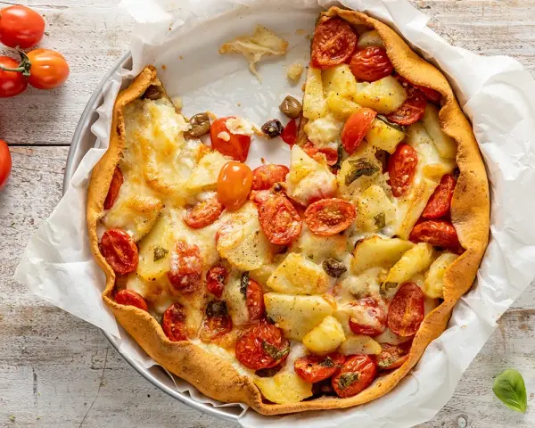 Torta salata estiva con patate, pomodorini e formaggio filante, un tripudio di sapori mediterranei.