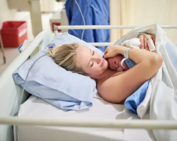 Szczęśliwa mama tuli noworodka. To początek jej urlop macierzyński, pełen miłości i czułości.