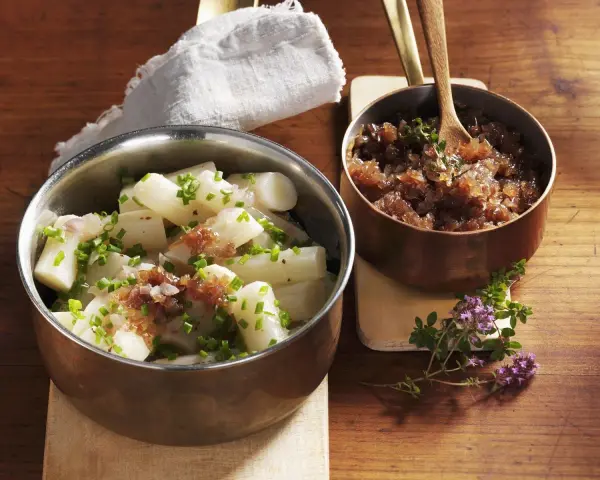 Ein köstliches Haferwurzel Rezept mit karamellisierten Zwiebeln und frischem Schnittlauch. Serviert in Kupfer- und Edelstahlschalen auf einem Holztisch.
