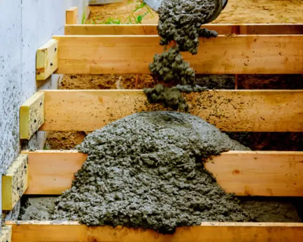 Vertido de hormigón en modernas escaleras exteriores de obra, con encofrado de madera y pared de hormigón.