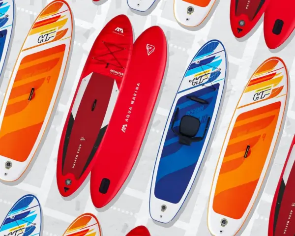 Bunte SUP-Boards, auch Stand-Up-Paddleboards genannt, liegen nebeneinander. Sie sind für Wassersportler gedacht.