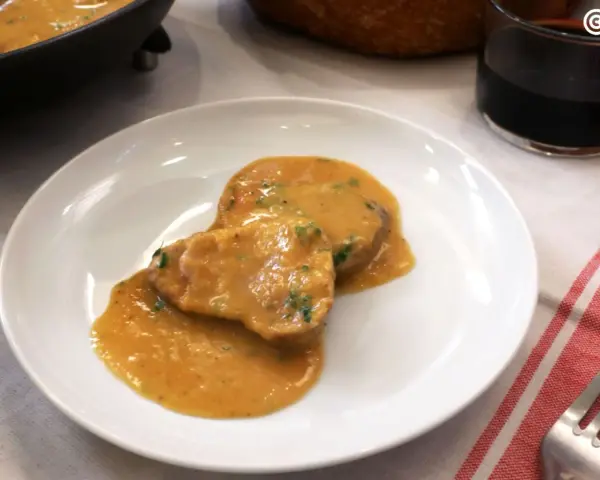 Dos medallones de solomillo al ajillo en una salsa cremosa, servidos en un plato blanco.
