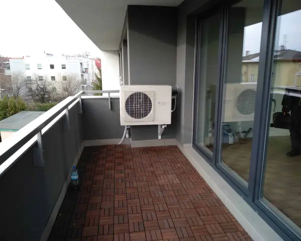 Klimatyzacja w bloku zamontowana na balkonie. Jednostka zewnętrzna chłodzi mieszkanie, zapewniając komfort.