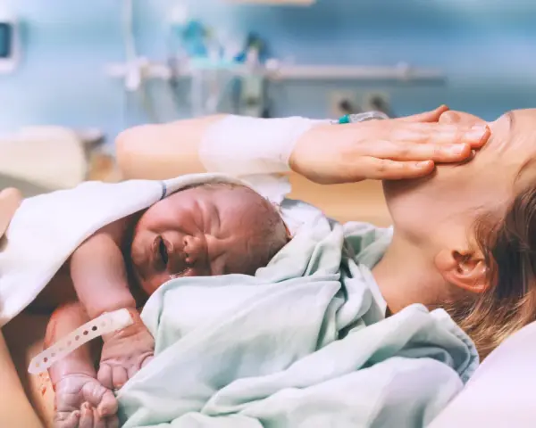 Nowy człowiek na świecie! Po długim porodzie, wyczerpana mama tuli swoje maleństwo.