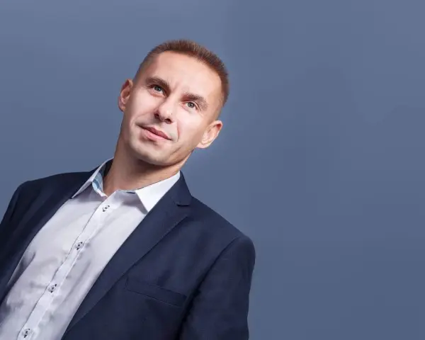 Mężczyzna w garniturze i białej koszuli, patrzący w górę.