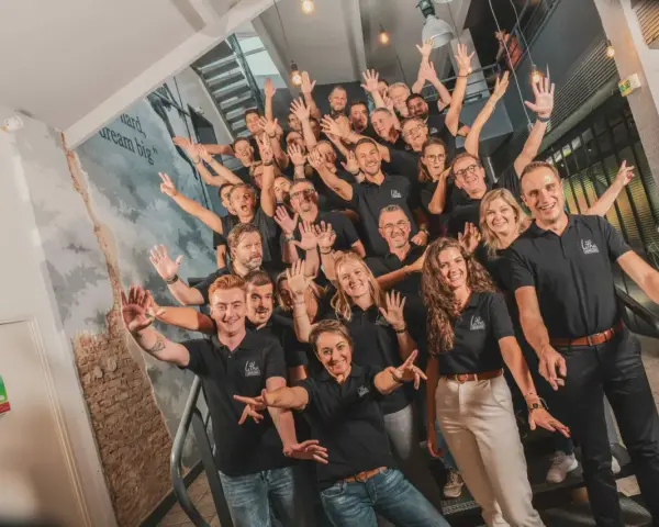 Une équipe souriante et joyeuse, unie pour un moment de **team building gratuit**. Ils montent les escaliers, bras levés, prêts à relever de nouveaux défis.