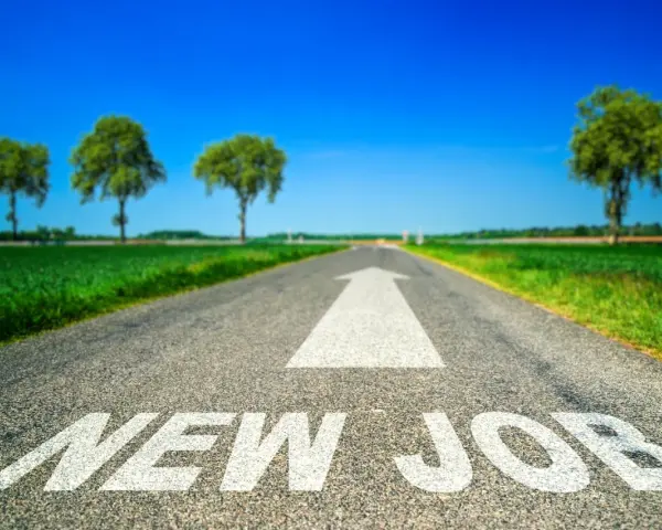 Strada asfaltata con freccia bianca e scritta "NEW JOB". Un percorso verso un futuro luminoso, ideale per chi sta pensando di cambiare lavoro a 30 anni.