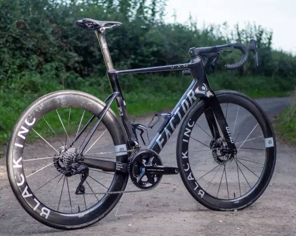 A black Factor Ostro VAM road bike with Black Inc wheels sits on a dirt path, ready for an adventure.