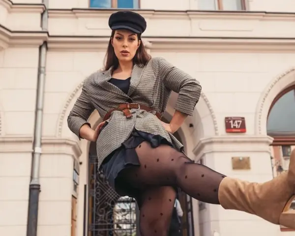 Kobieta w czapce i marynarce w kratę, z nogą uniesioną do przodu. Czy to rozmiar damski 44?