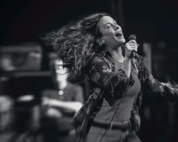 Energetyczny alanis morissette koncert, wokalistka śpiewa z pasją, włosy rozwiane w locie.