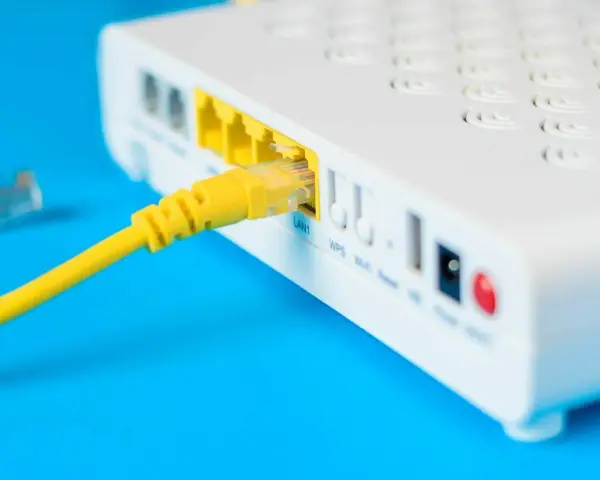Żółty kabel sieciowy podłączony do portu LAN routera i modemu.