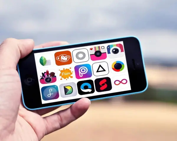 Dłoń trzyma telefon z ikonami aplikacji do edycji zdjęć na Androida.