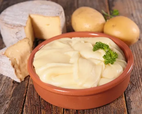 Aligot receta: puré cremoso de patatas y queso, con patatas y queso de cabra al lado.