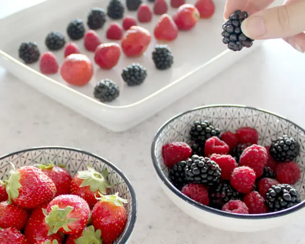 Frische Beeren, darunter Erdbeeren, Himbeeren und Brombeeren, werden für die Lagerung vorbereitet. Man kann Erdbeeren einfrieren, um sie später zu genießen.